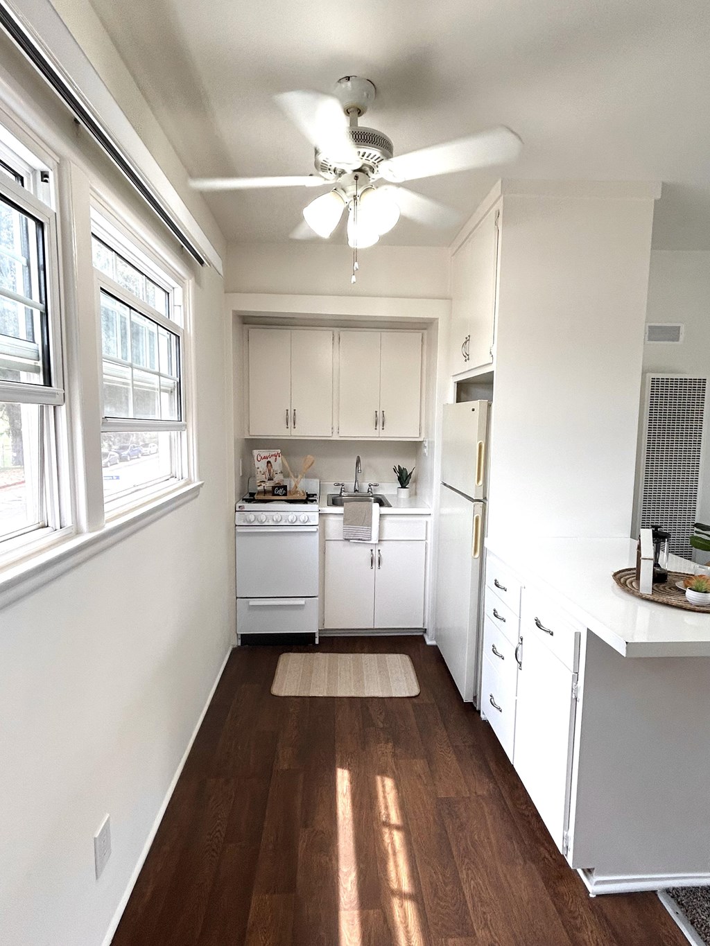 A kitchen with white cabinets and a fan on the ceiling.