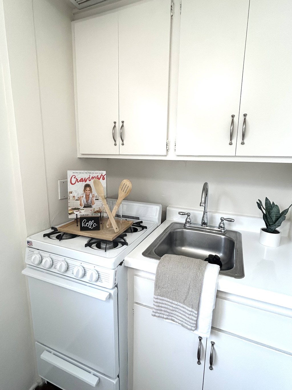 A white kitchen with a stove and sink.