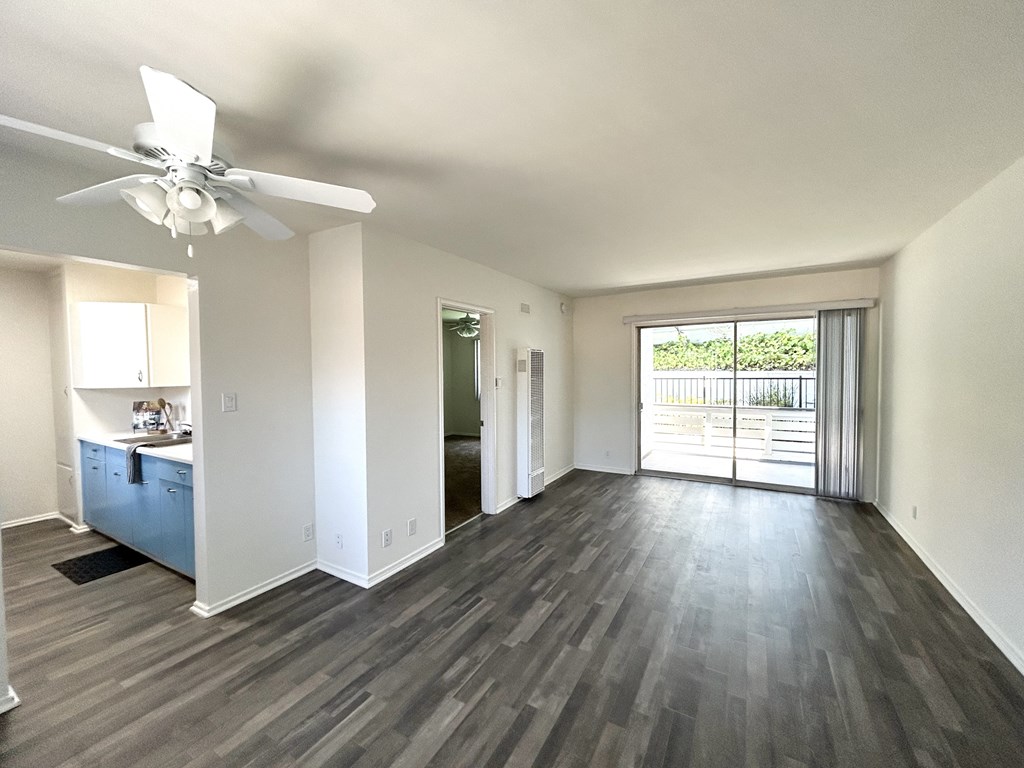 A room with a ceiling fan and sliding glass doors.