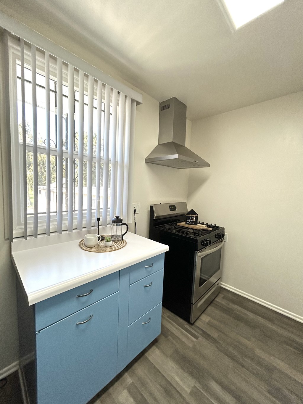A kitchen with a stove and a window with blinds.