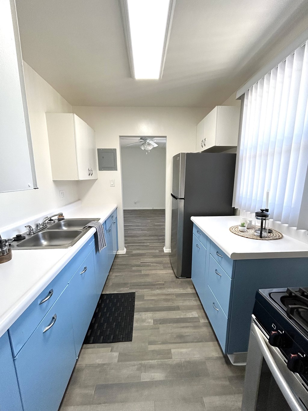 A kitchen with blue cabinets and a black refrigerator.