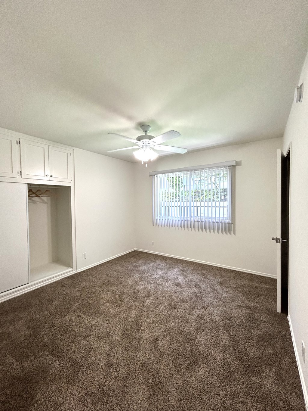 A room with a ceiling fan and carpeted floor.