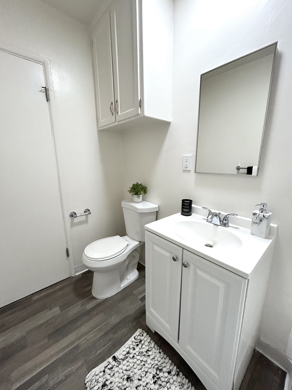 A white bathroom with a toilet, sink, and mirror.