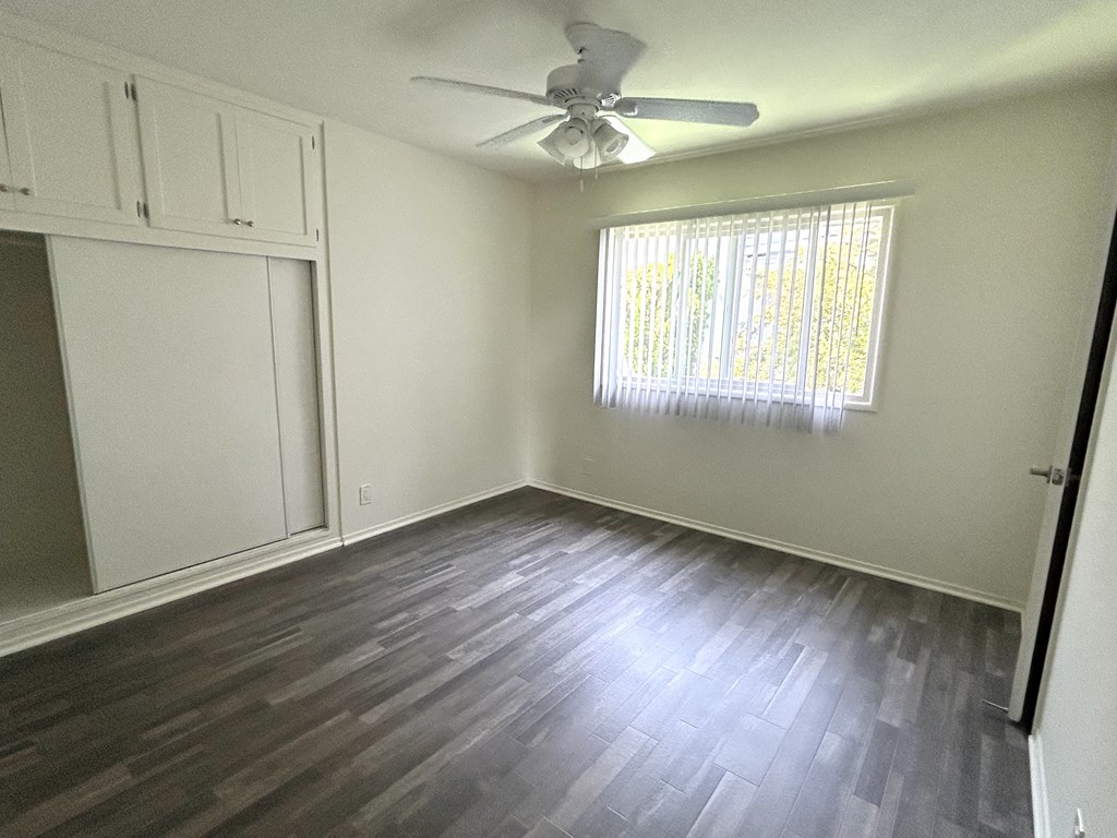 A room with a ceiling fan and a window with blinds.