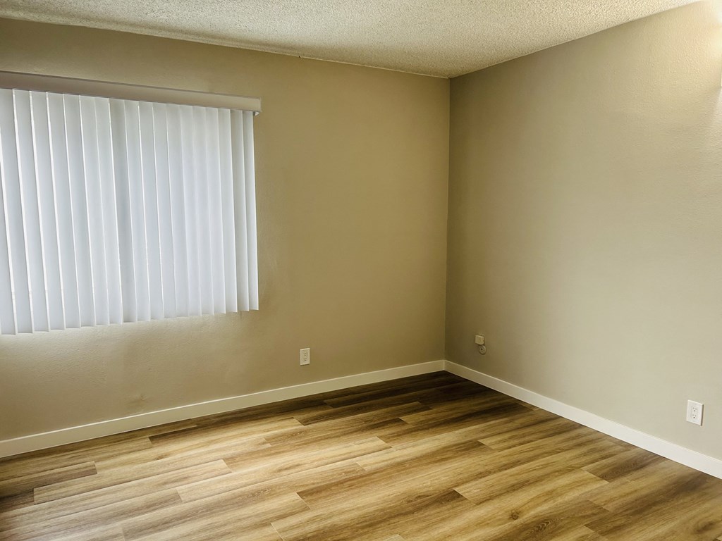 an empty room with a window and wooden floors