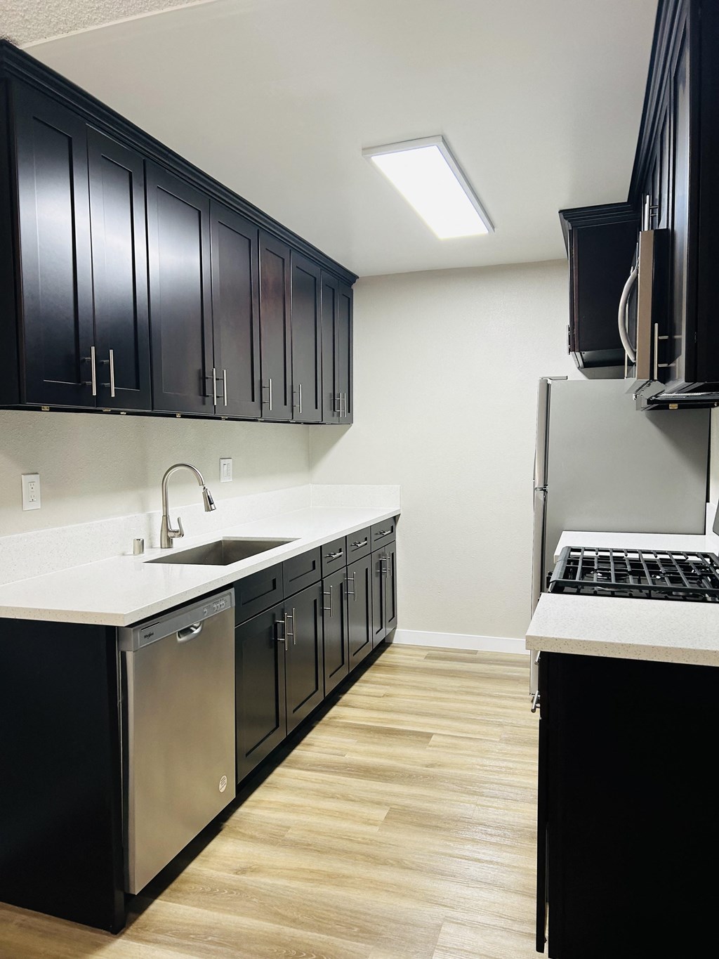 a kitchen with black cabinets and a sink and a refrigerator