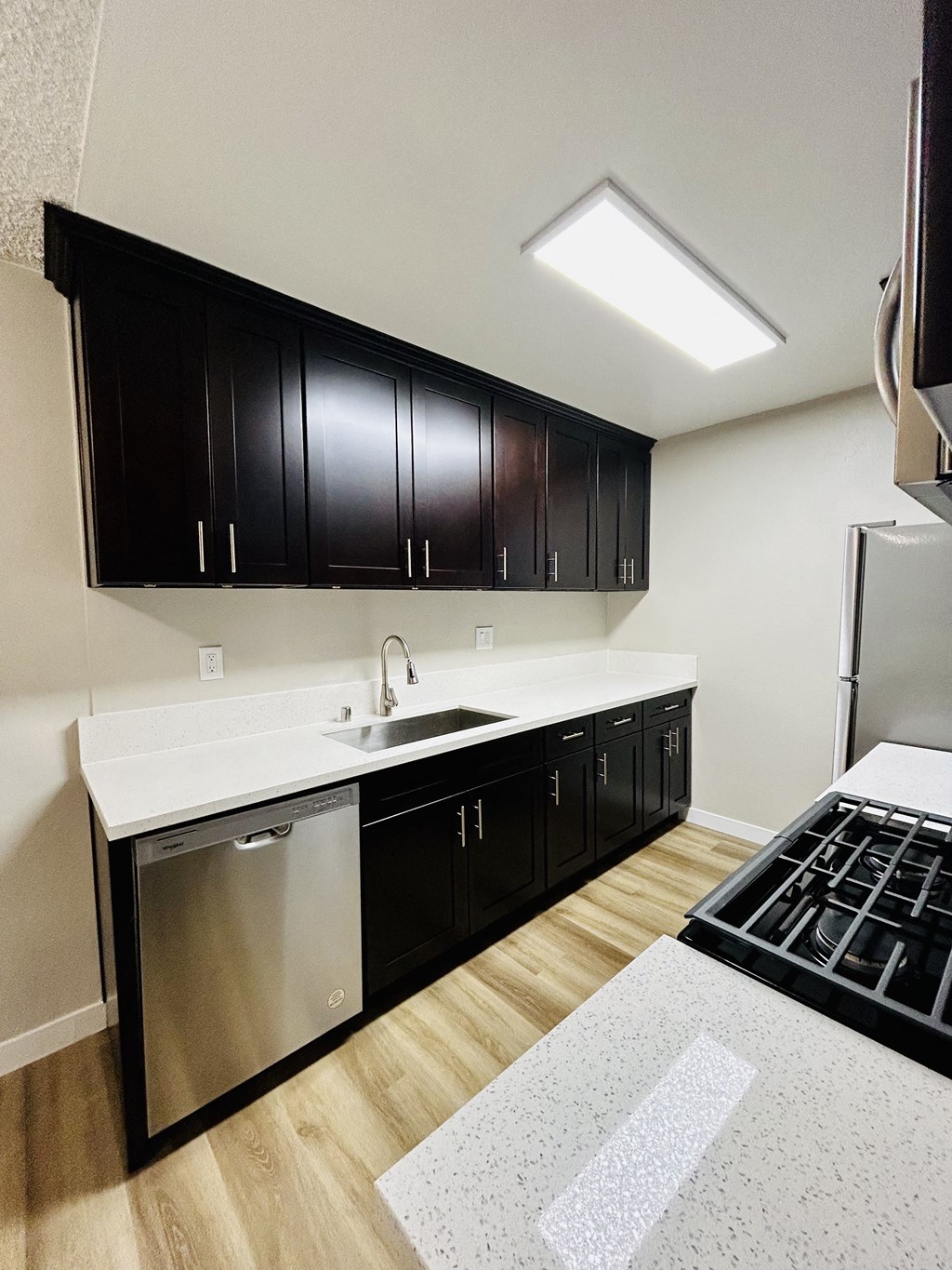 a kitchen with black cabinets and a white counter top and a stove and refrigerator
