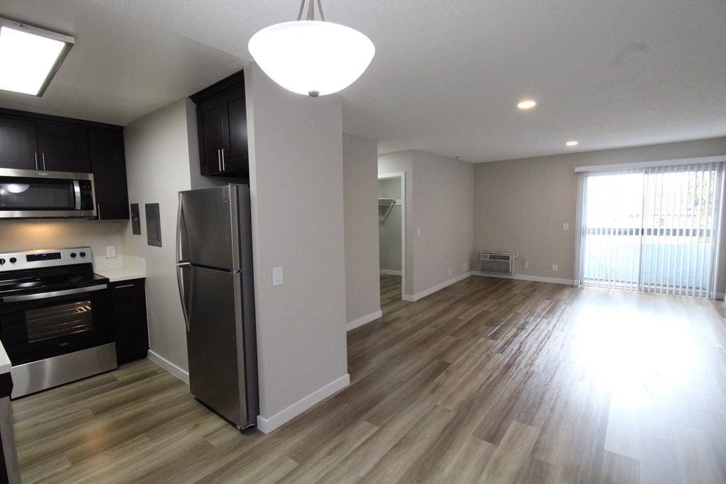 a renovated kitchen and living room with wood flooring and stainless steel appliances