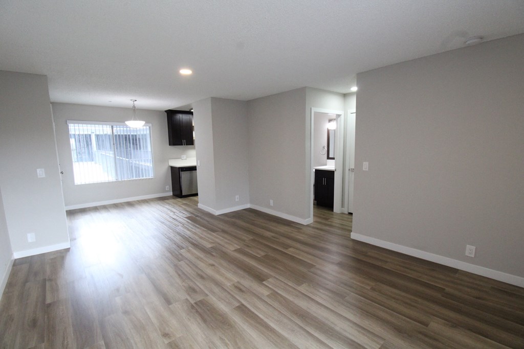 an empty living room with wooden floors and a window