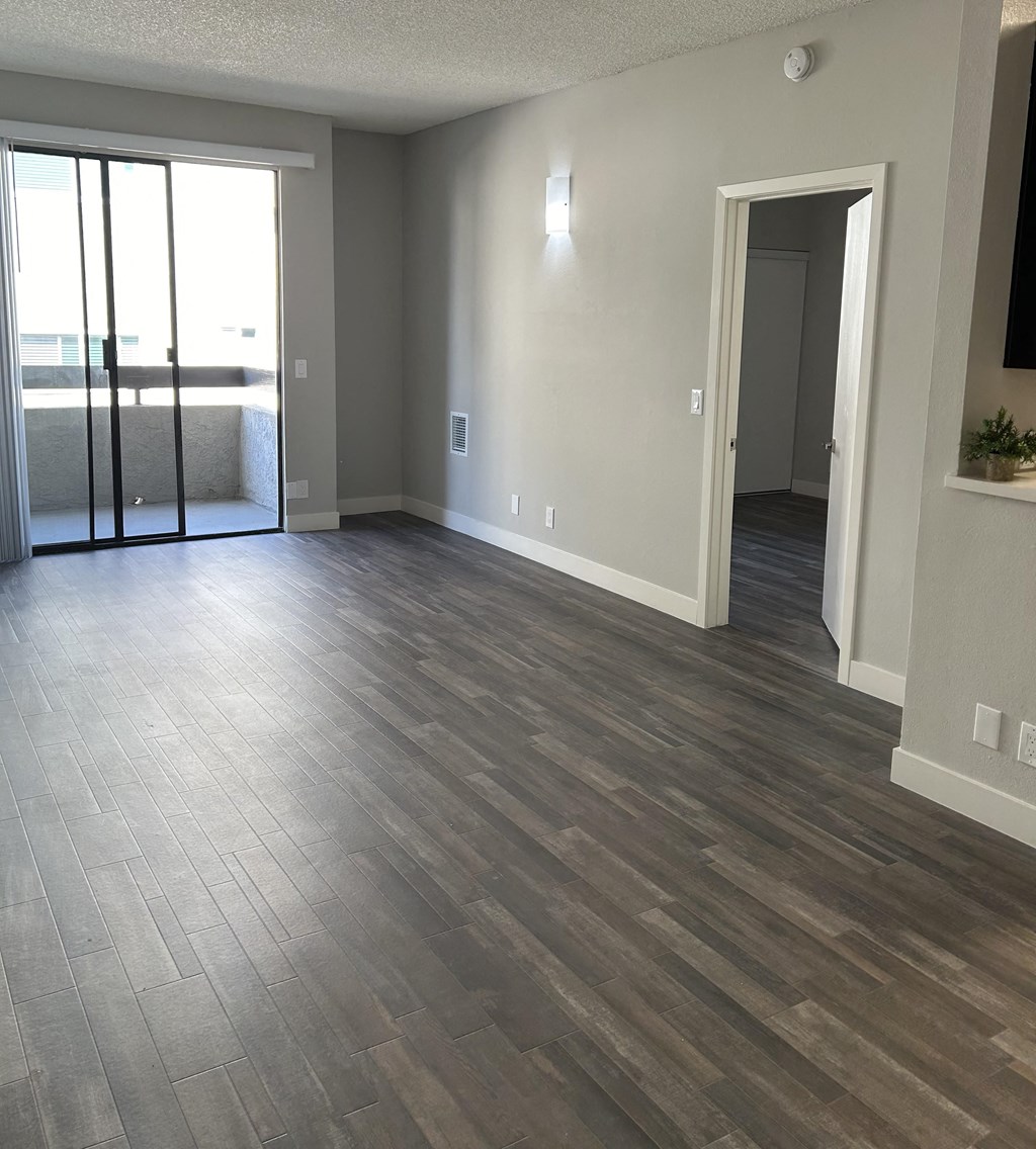 an empty living room with wood flooring and a balcony
