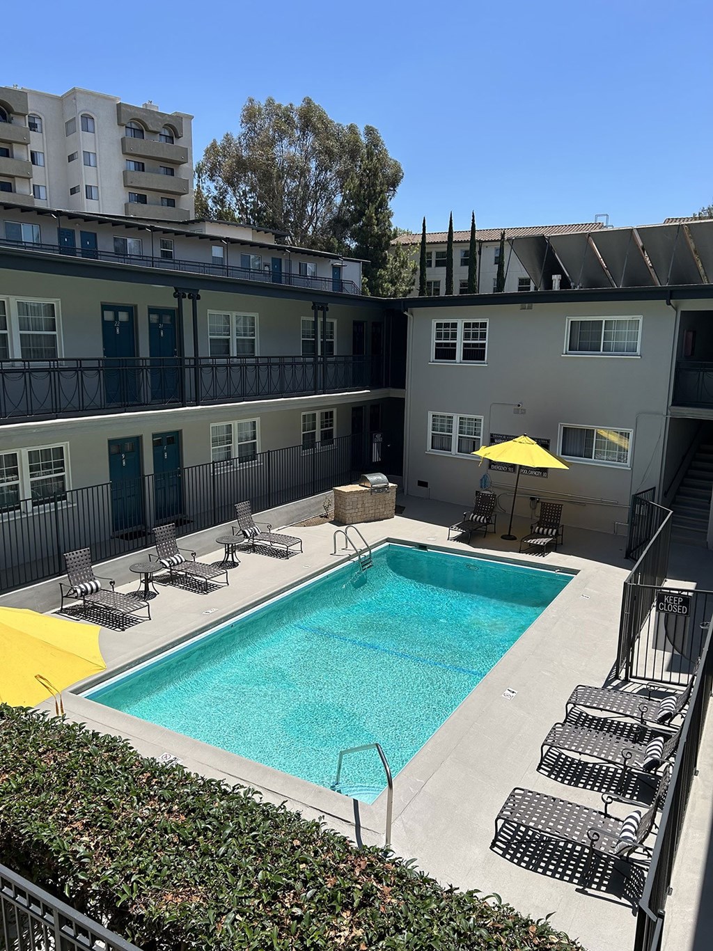 A swimming pool is surrounded by chairs and a building.