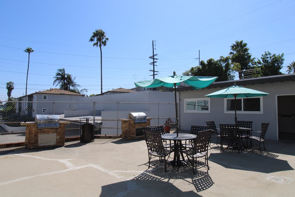 a patio with a grill and tables and umbrellas