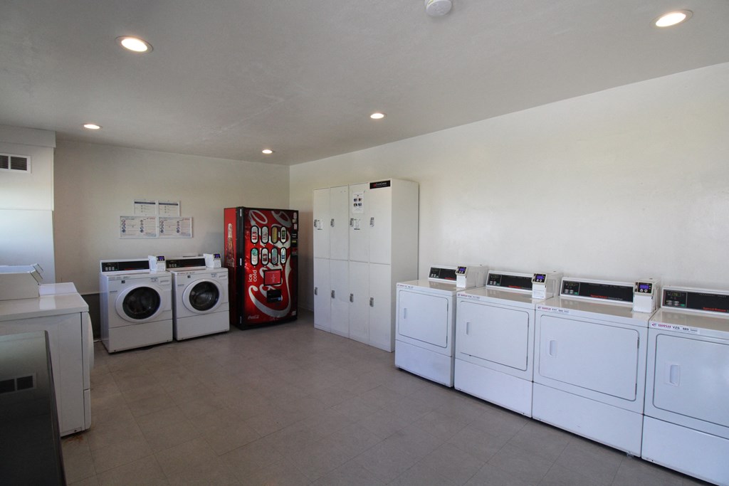 a laundry room with white washers and dryers and a red vending machine