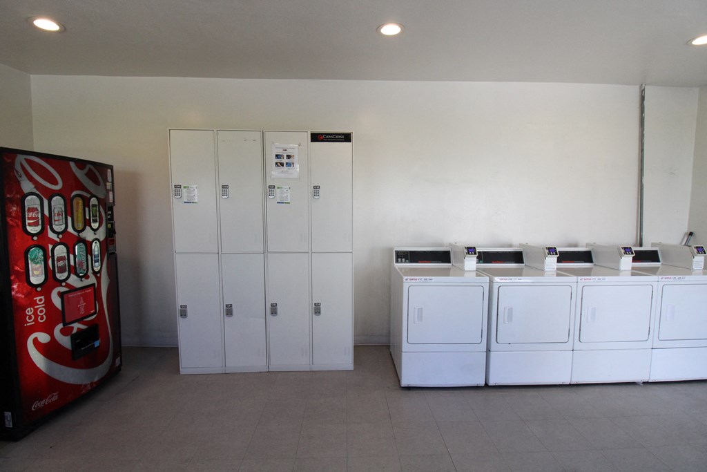 a laundry room with white washers and dryers and a vending machine