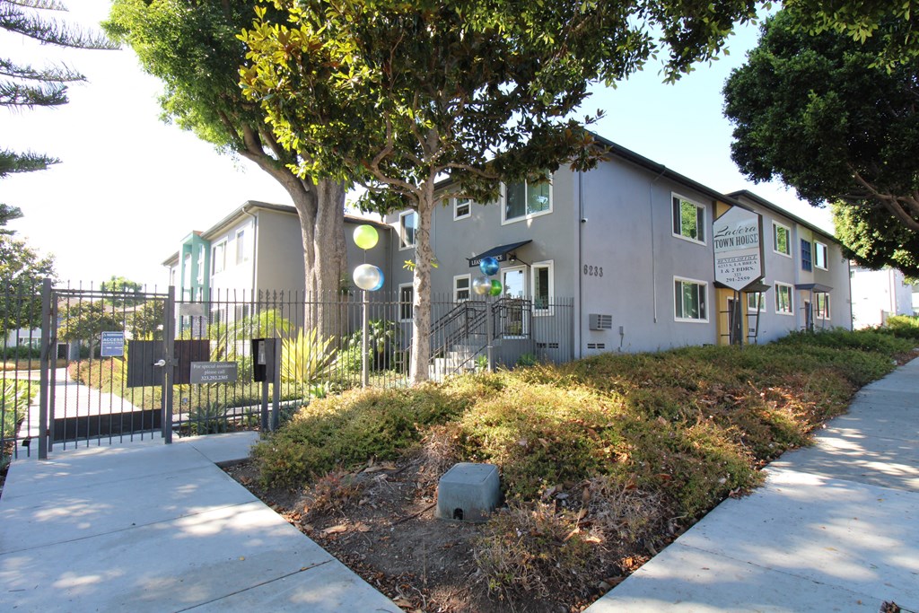 a building with a fence and a sidewalk in front of it