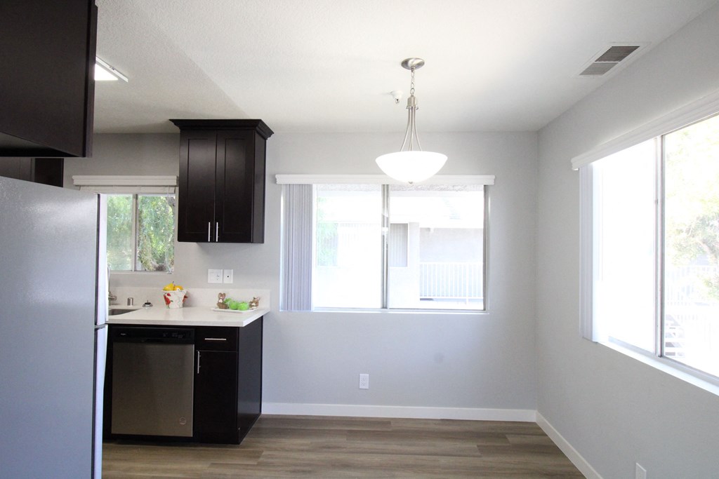 A kitchen with black cabinets and a stainless steel refrigerator