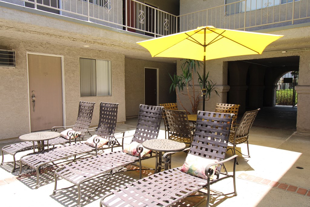 a patio with chairs and tables and a yellow umbrella