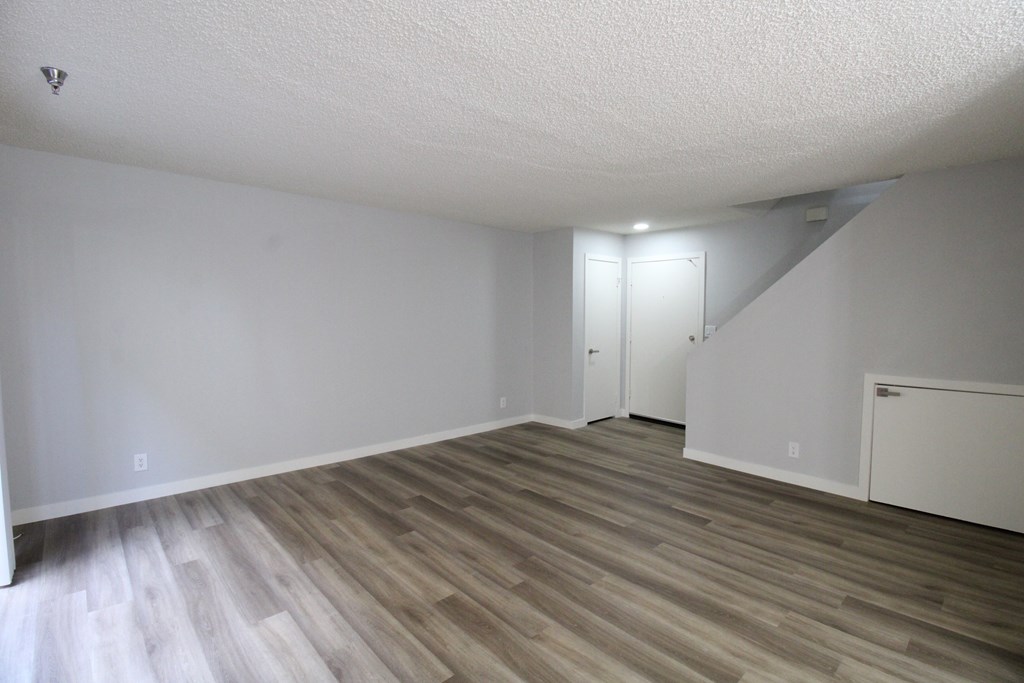 A room with wooden flooring and white walls.