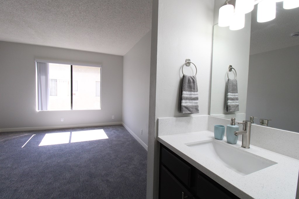 A bathroom with a sink, mirror, and towel rack.