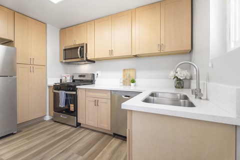 A kitchen with wooden cabinets and a stainless steel refrigerator.