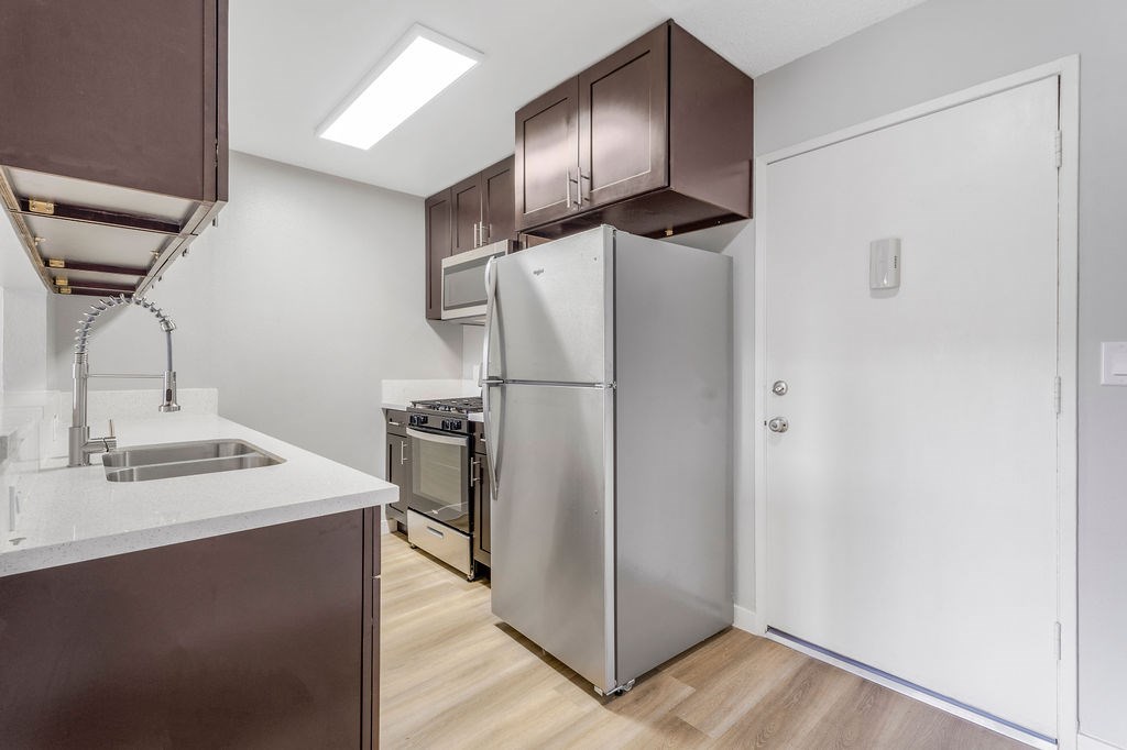 A modern kitchen with a stainless steel refrigerator and a white sink.