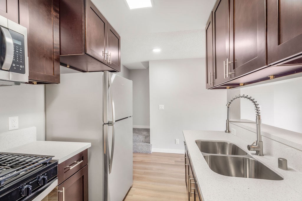 A kitchen with a stove, refrigerator, and sink.