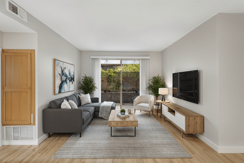 A living room with a grey couch, a coffee table, a chair, and a painting on the wall.