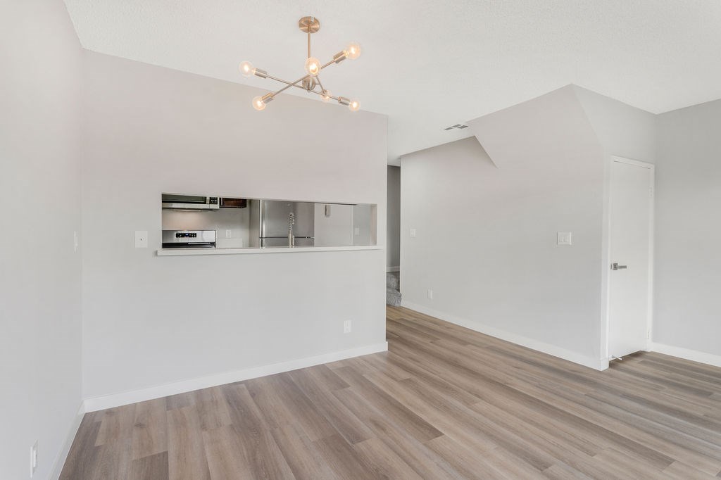 A modern kitchen with a wooden floor and a chandelier.