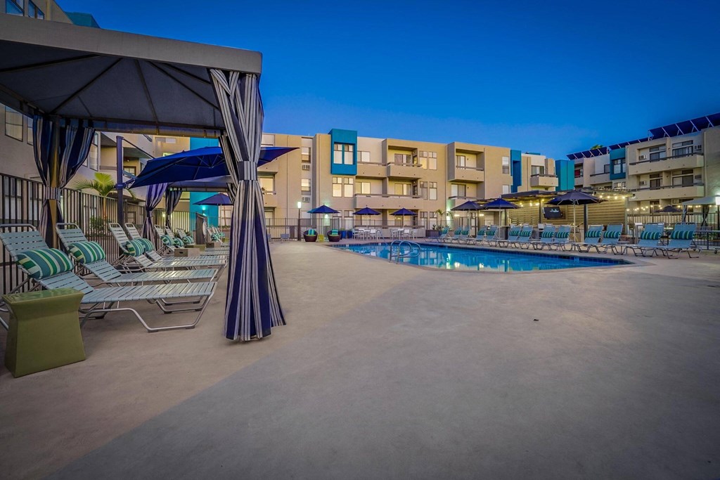 a resort pool with chairs and umbrellas at night
