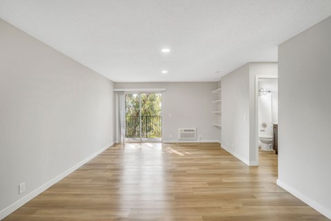 A spacious room with wooden floors and white walls.