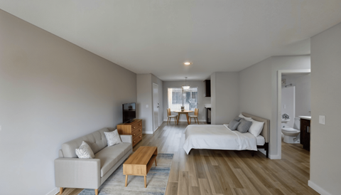 A modern bedroom with a white bed and wooden floors.