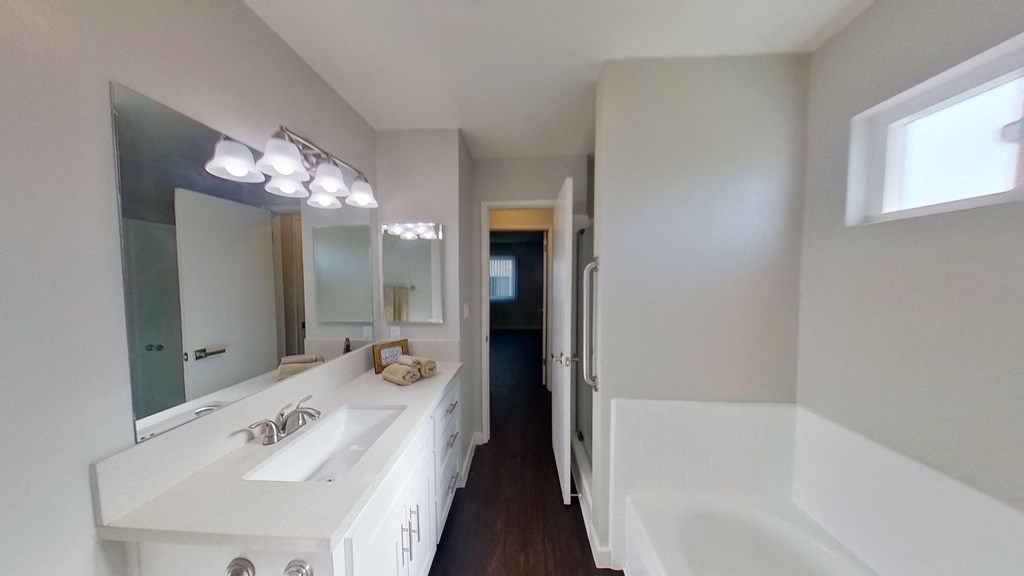 a bathroom with a large mirror and a sink and a tub
