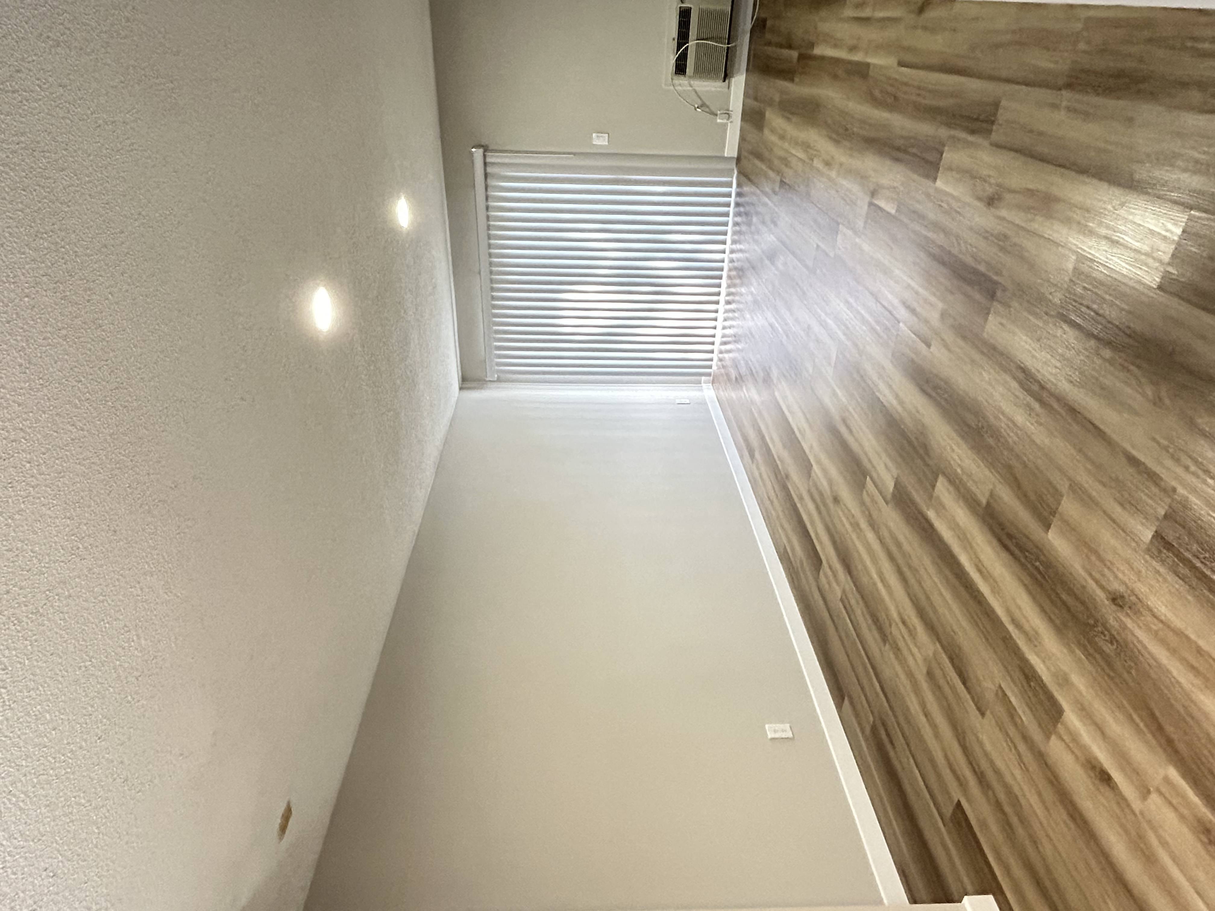 a long hallway with wood flooring and a window