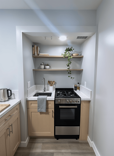 A kitchen with a black stove top oven and wooden cabinets.