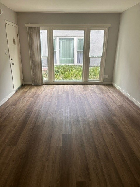 an empty living room with wood floors and a window