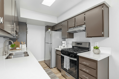 A modern kitchen with brown cabinets and stainless steel appliances.