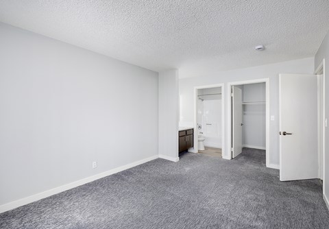 A sparsely furnished room with a carpeted floor and white walls.