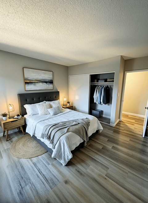 A bedroom with a large bed and a wooden floor.