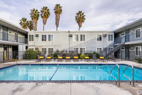 A swimming pool in front of a building with palm trees in the background.