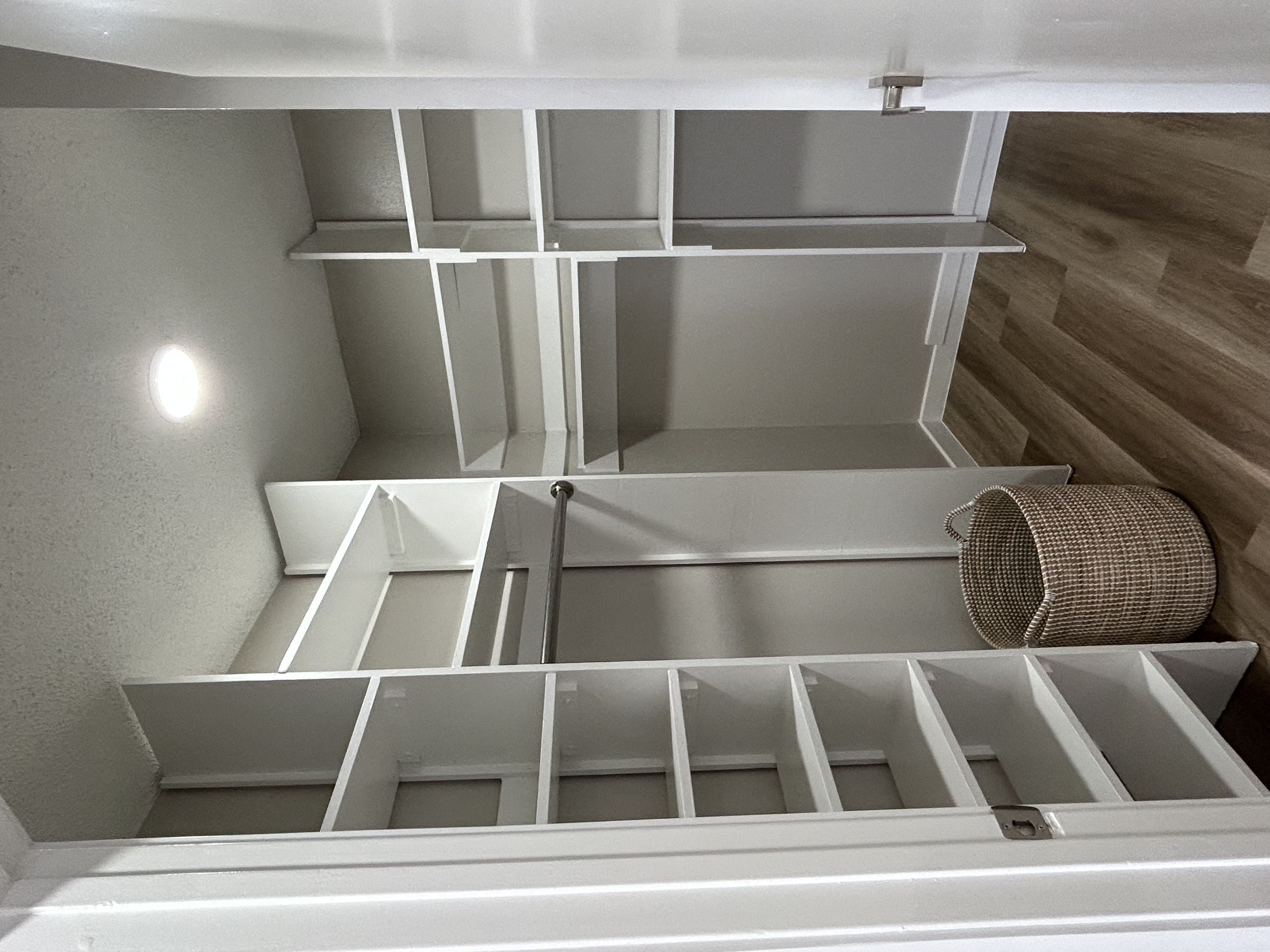 a walk in closet with built in white shelves and a basket in it and a shoe shelf