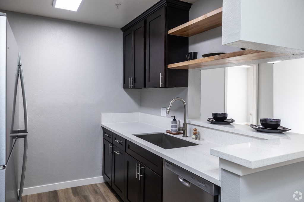 A modern kitchen with black cabinets and white countertops.