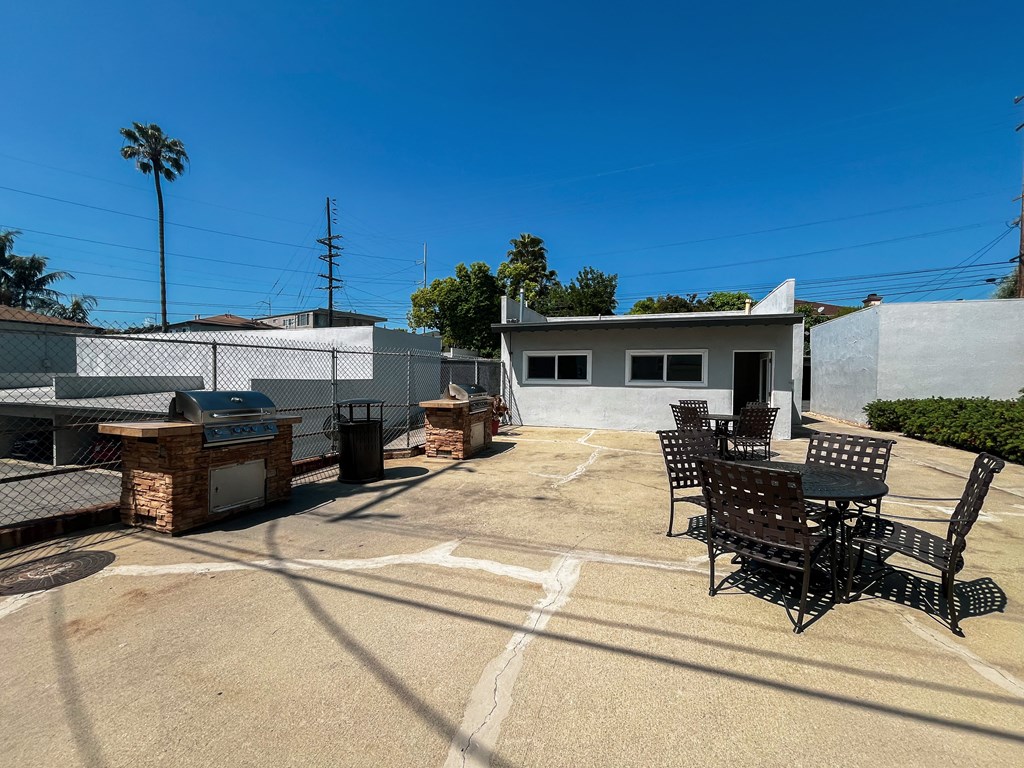 a patio with a table and chairs and a grill