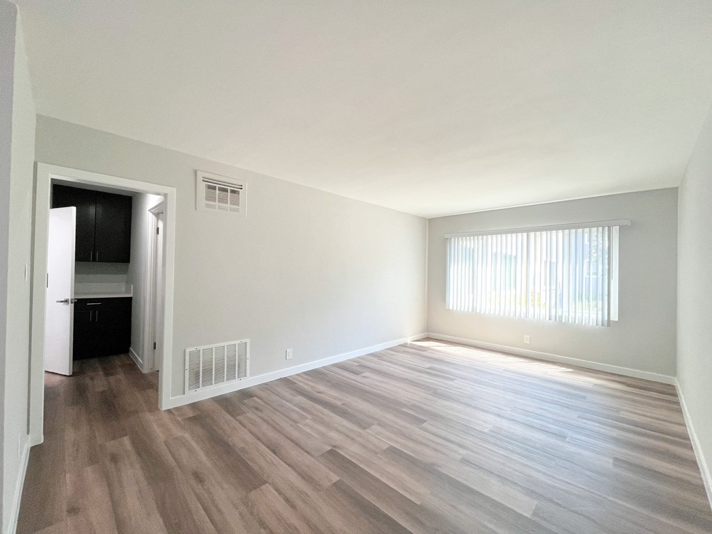 an empty living room with wood flooring and a window