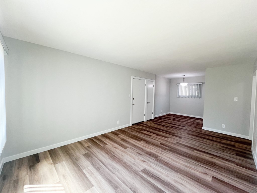 the living room and dining room of an apartment with wood flooring