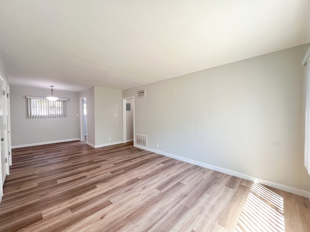 an empty living room with wood flooring and white walls