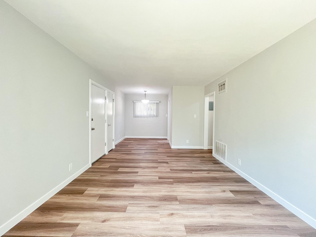 the living room and hallway of a new home with wood flooring