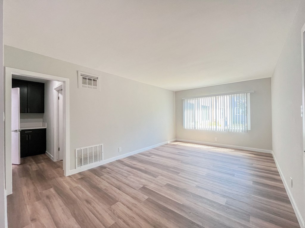 an empty living room with wood flooring and a window