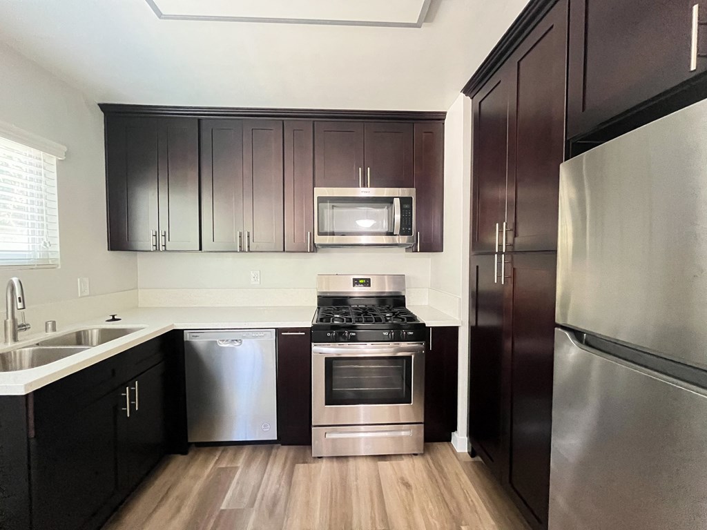 a kitchen with stainless steel appliances and dark wood cabinets