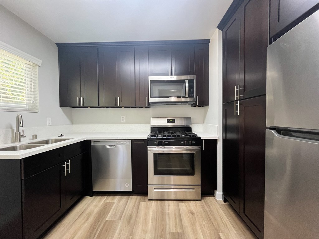 an empty kitchen with stainless steel appliances and black cabinets