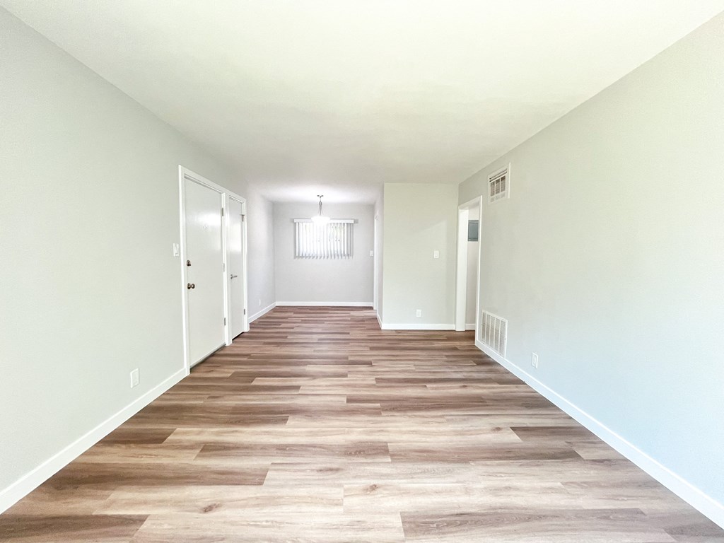 an empty hallway with wood flooring and white walls